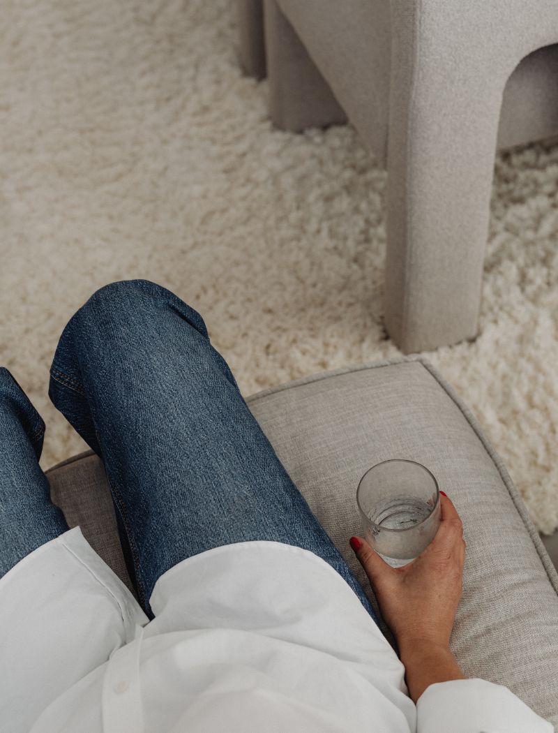 A person sitting on a couch holding a glass of water.